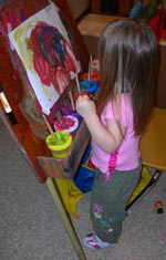 Little girl painting at easel